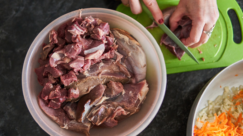 Woman's hands cutting venison, with closeup of bowl cuts of the meat