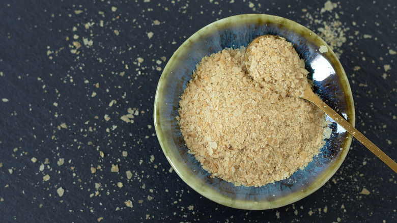 A bowl of nutritional yeast flakes is photographed from above.