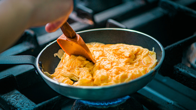 Person preparing scrambled eggs in a pan.
