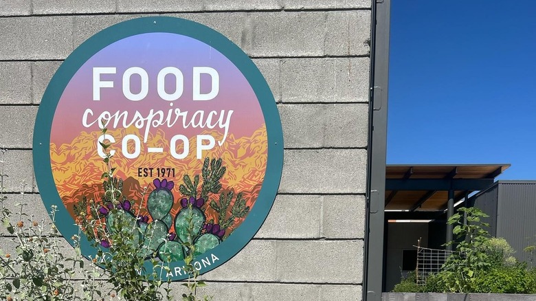 Round sign hung on concrete block wall that reads "Food Conspiracy Co-Op Est 1971"