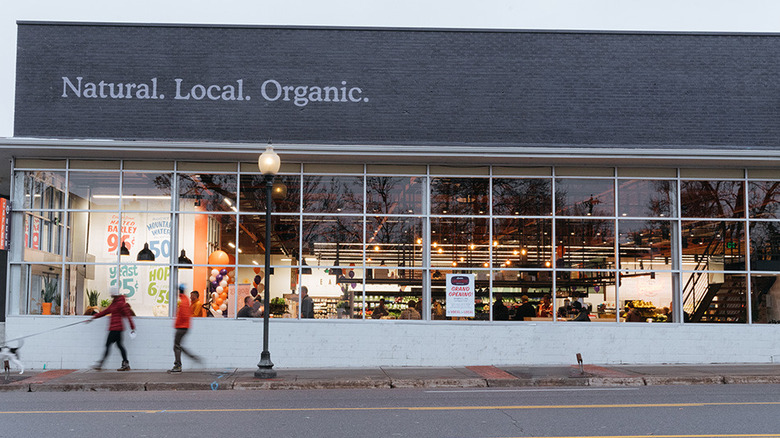 People walking on sidewalk past Leevers Locavore grocery store
