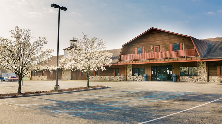 Parking lot with blooming trees in front of wooden grocery store