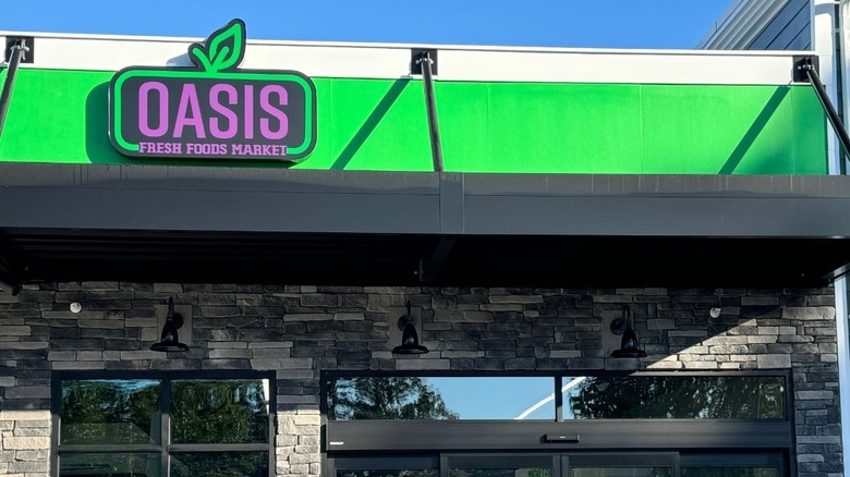 Entrance of a grocery store with a bright green and purple sign