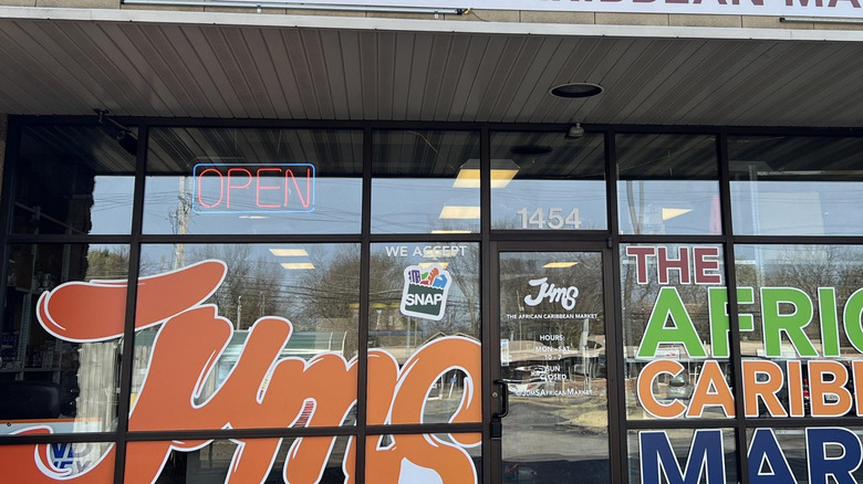 Glass storefront with colorful window paint that reads "Jums The African Caribbean Market"