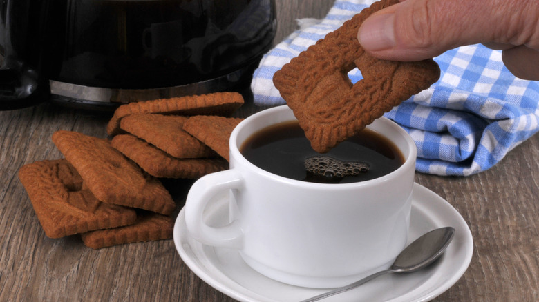 Person dipping speculoos cookie into cup of coffee