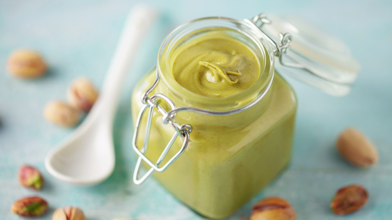 Pistachio cream and nuts on blue surface