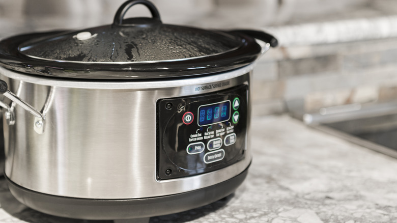Steamy slow cooker sitting on kitchen counter