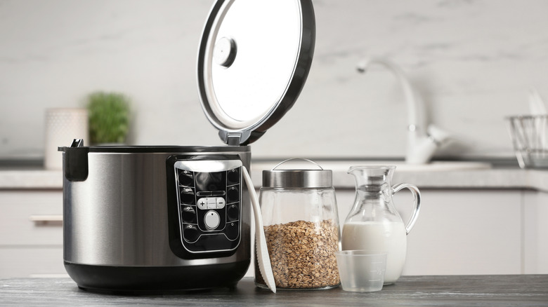 Jars of milk and oatmeal next to an open slow cooker
