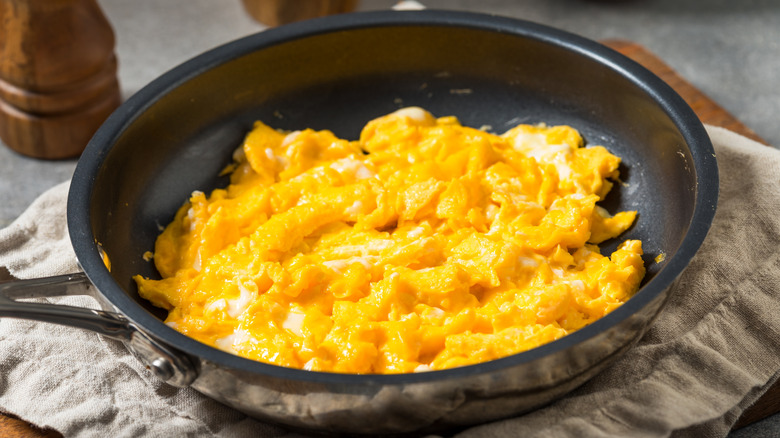 Scrambled eggs served in a pan with a thick cloth underneath
