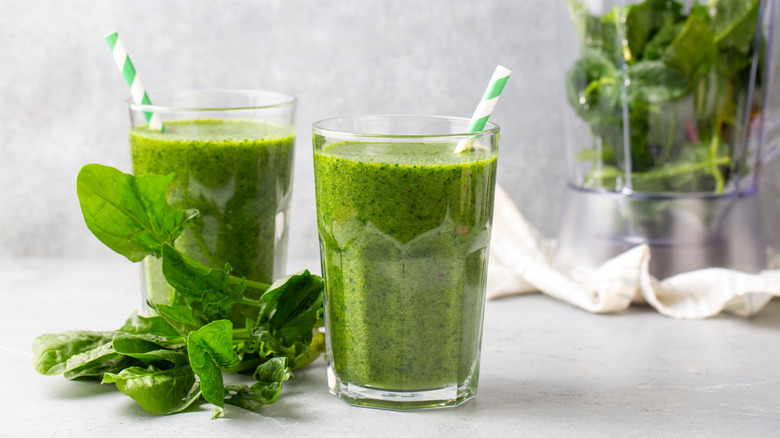 two glasses of green smothie with straws