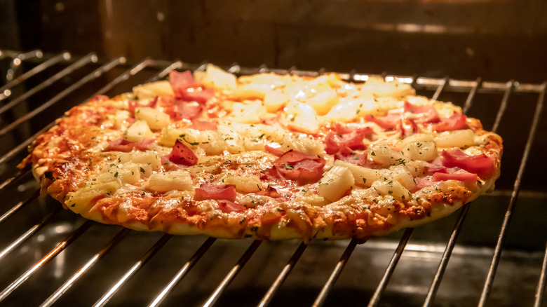 A frozen pizza bakes on a rack in the oven.