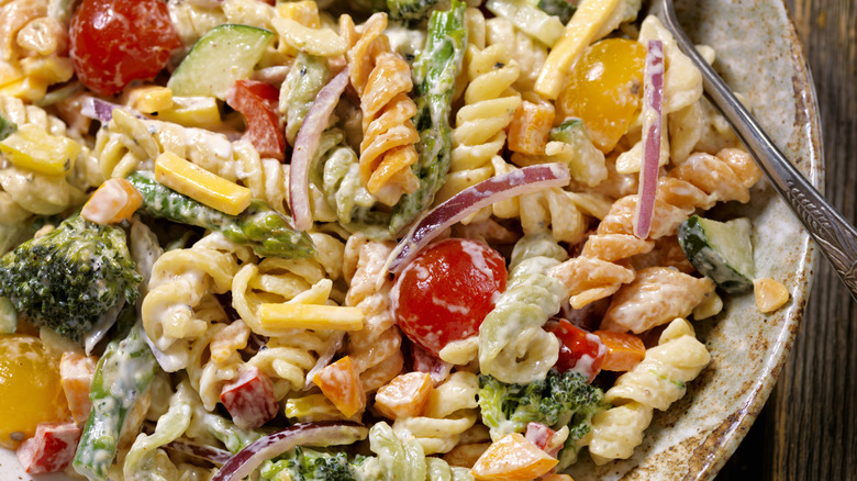 pasta salad in a bowl with dressing an vegetables