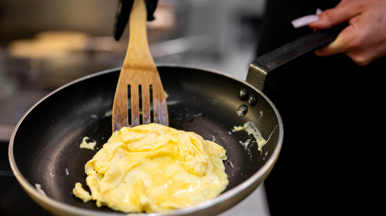 Person serving scrambled eggs from a pan