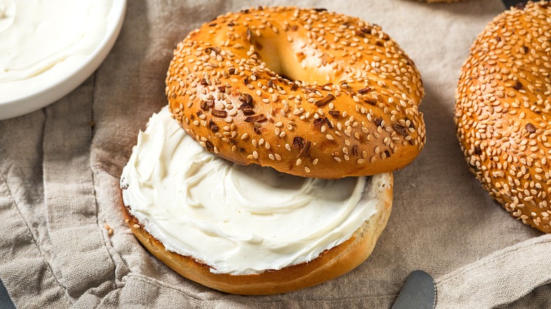 Halved everything bagel with cream cheese on a taupe-colored cloth napkin.