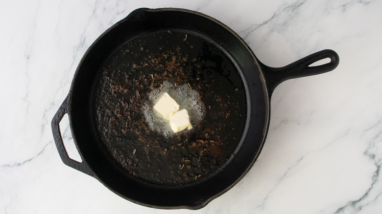 Two pats of butter melting in a large skillet