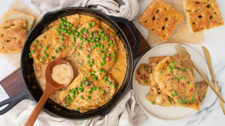 Overhead shot of chicken a la king, plated and in skillet served with focaccia.