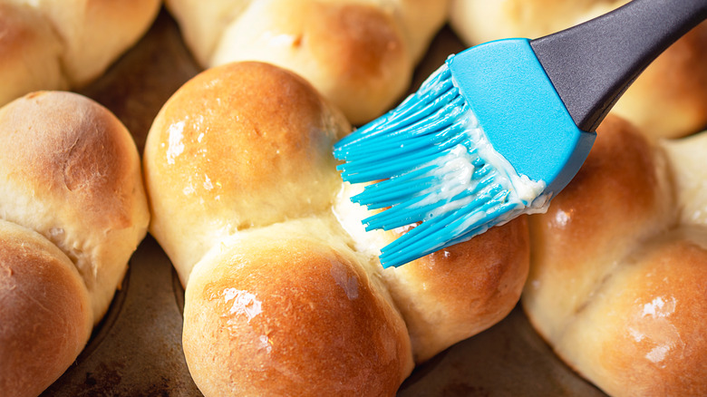 Dinner rolls being brushed with melted butter