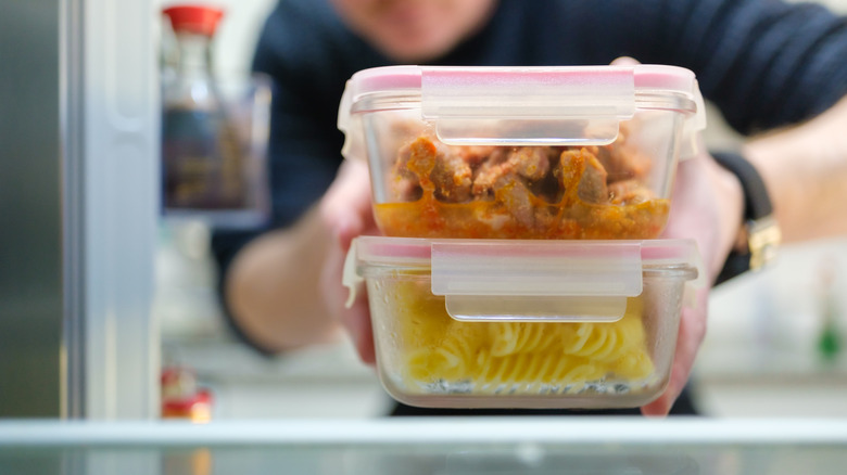 Man taking cooked pasta and chicken leftovers from the refrigerator