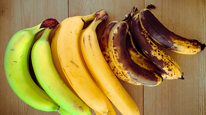 Bananas of different stages of ripening on wooden surface