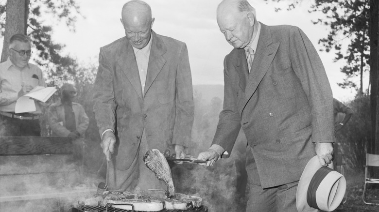 Dwight Eisenhower and Herbert Hoover grilling a steak outdoors