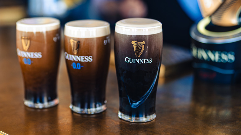 Three Guinness pints on a bar counter.
