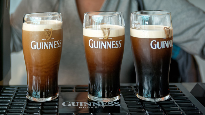 Three Guinness pints on a bar counter.