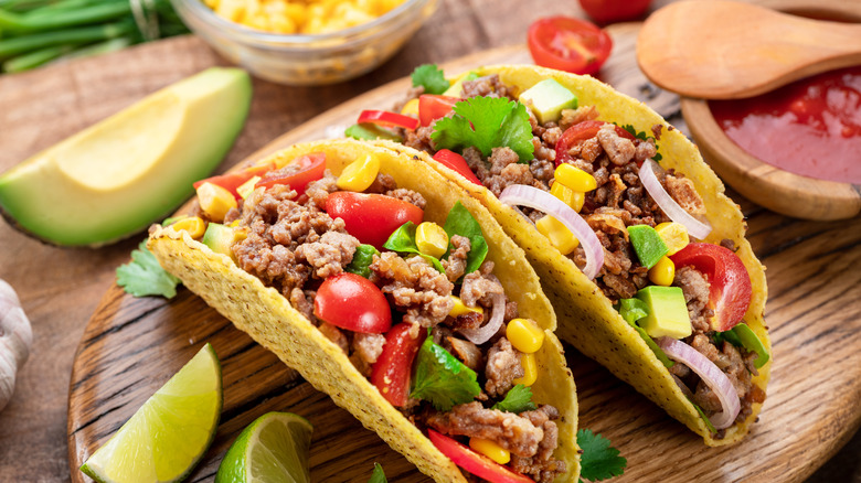 Tacos on a cutting board seasoned with Tajín.