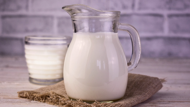 A glass pitcher of buttermilk on a burlap cloth