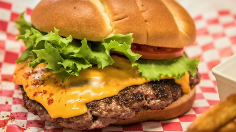 A smashburger is pictured on a checkered wrapper in closeup.