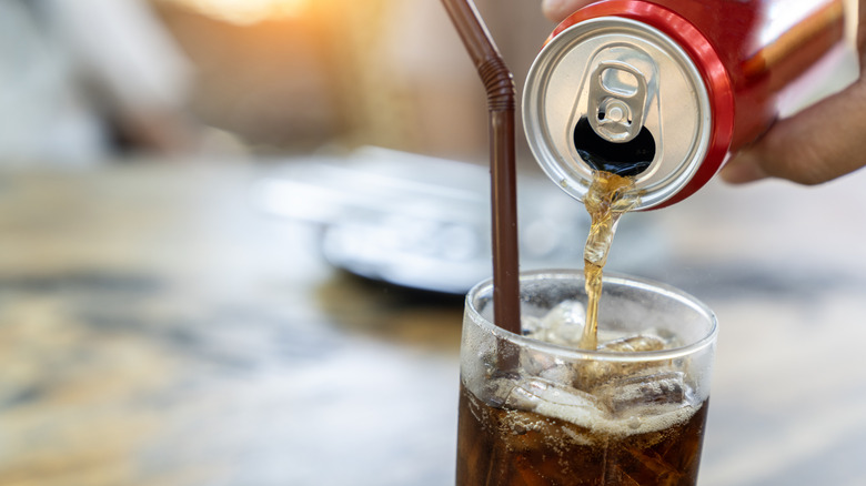 Can of soda pouring into glass
