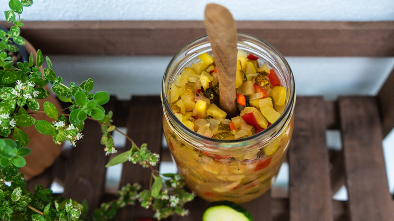 A jar of zucchini relish with wooden spoon