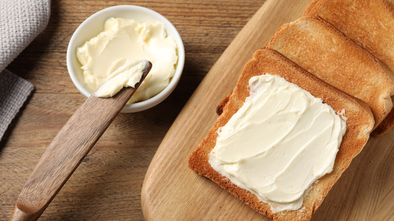 Slices of bread with butter next to a bowl of butter and a knife