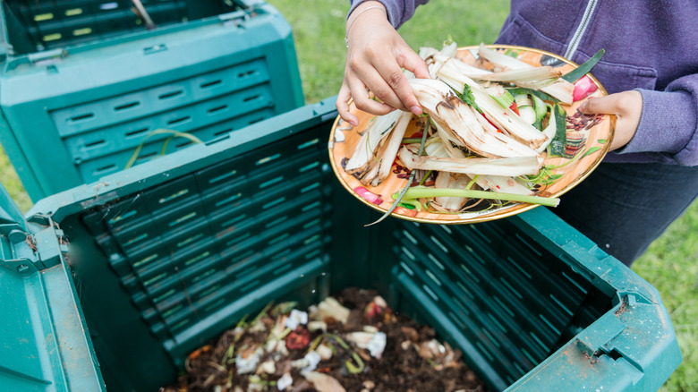 A woman tossing food scraps into a compost bin