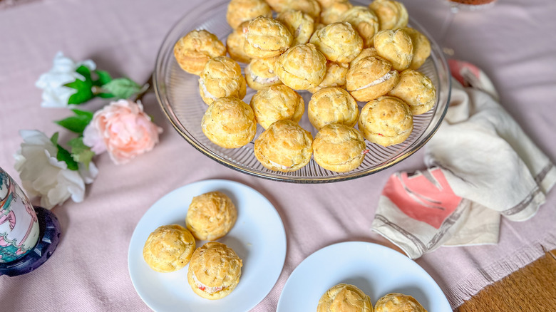 Valentine's Day gruyere and crab gougerès on serving platter and plates on table with flowers