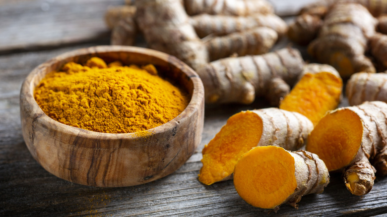 powdered turmeric next to turmeric root