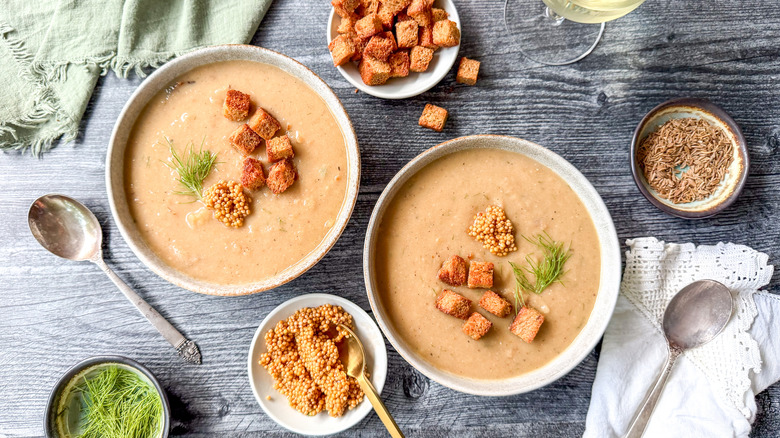 Vegan Nordic-style creamy cabbage soup in serving bowls with rye croutons, fresh dill sprigs, and pickled mustard seeds