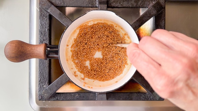 Pickled mustard seeds simmering in saucepan