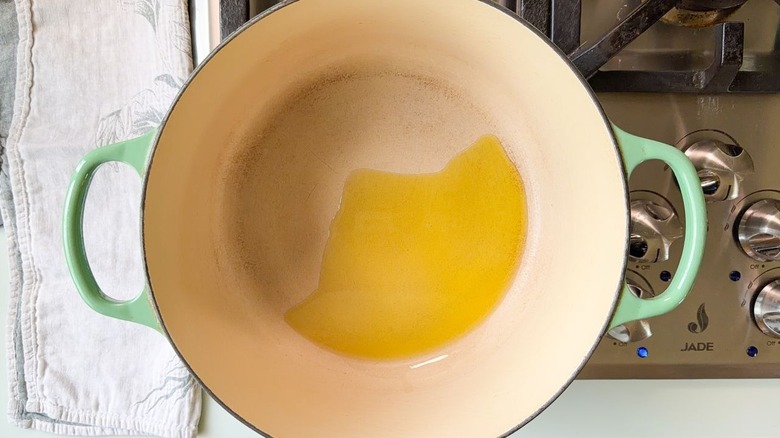 Olive oil heating in green Dutch oven on stovetop
