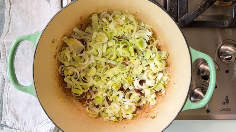 Sliced leeks in green Dutch oven on stovetop