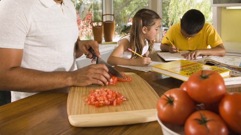 Person chopping tomatoes on board
