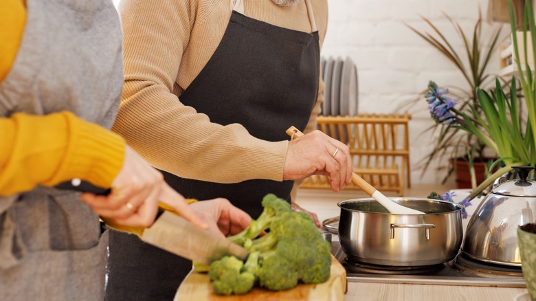 Couple chopping up broccoli