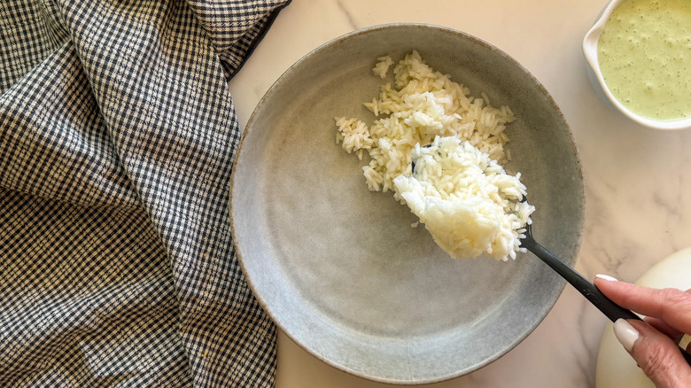 hand spooning rice into bowl