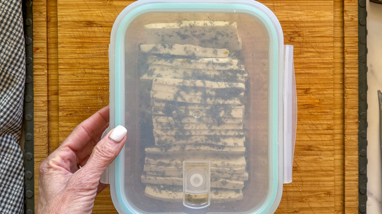 hand covering tofu in container