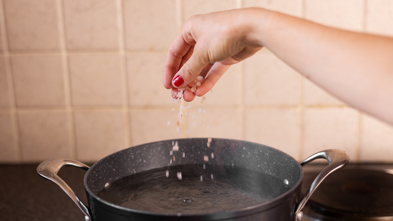 hand sprinkling salt into water 
