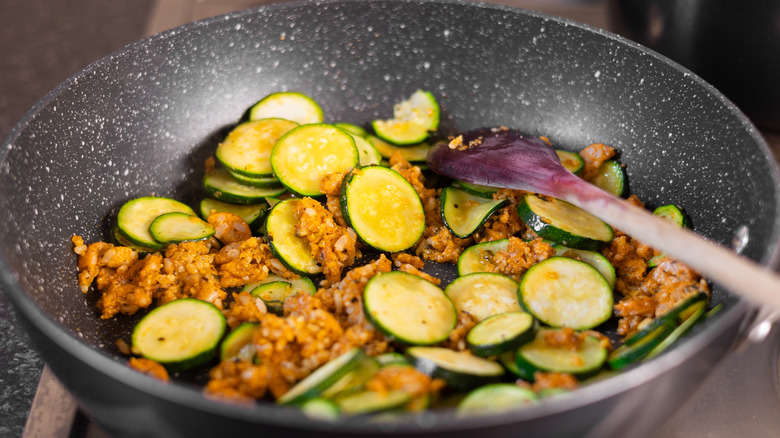 zucchinis and vegetarian sausages in pan 