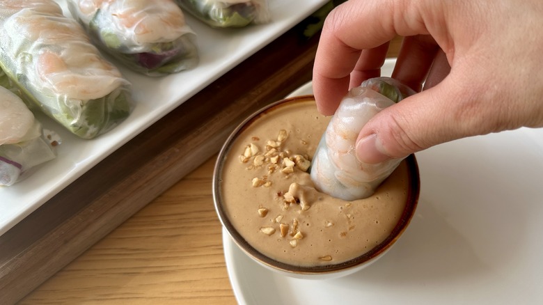 dipping shrimp roll in sauce