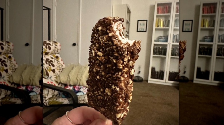 Chocolate eclair bar in hand in a room