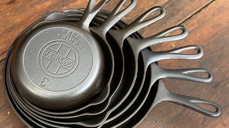 A set of Griswold cast iron pans likely made before 1957 stacked together with the top overturned to show the logo and heat rings.