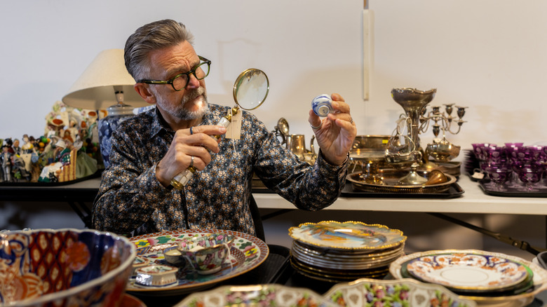 A man studies various vintage ceramics as collectible items.