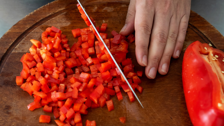 person chopping red bell pepper